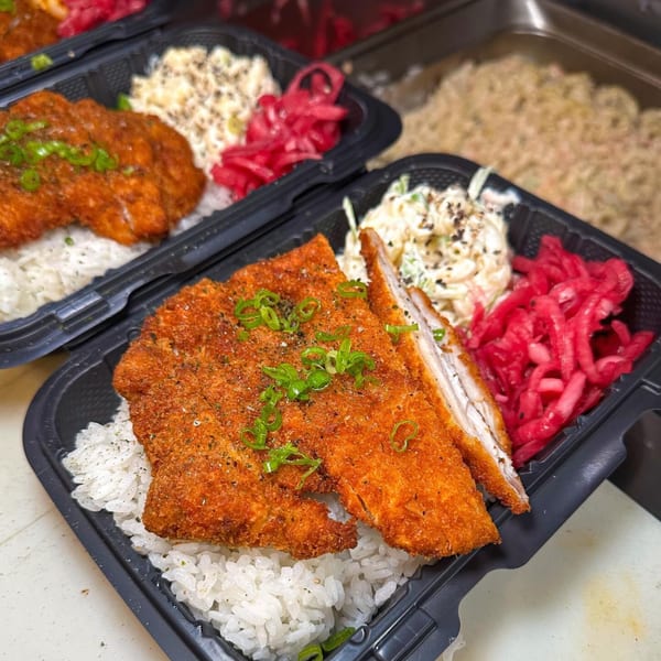 Two takeout containers with crispy fried chicken, white rice, coleslaw, and pickled red cabbage.