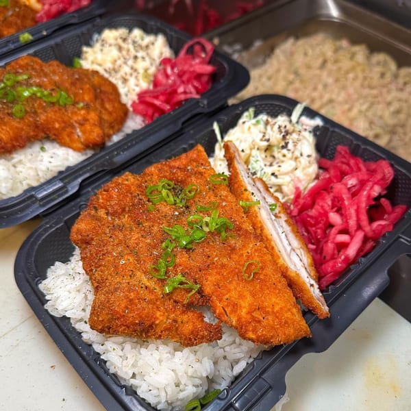 Two takeout containers with crispy fried chicken, white rice, coleslaw, and pickled red onions.