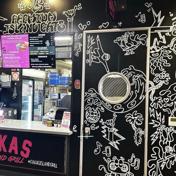 A restaurant counter with a menu board and a black wall with white cartoon-style drawings.