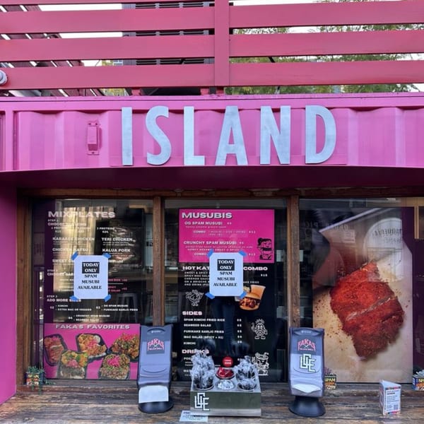 Pink food truck with "ISLAND" in silver letters, displaying menus and food items.