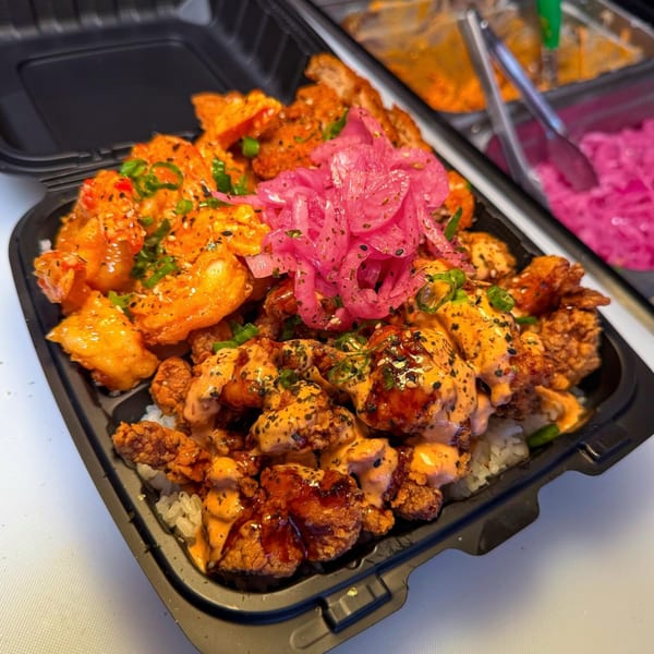 A takeout container filled with rice, fried chicken, shrimp, and pickled red onions.