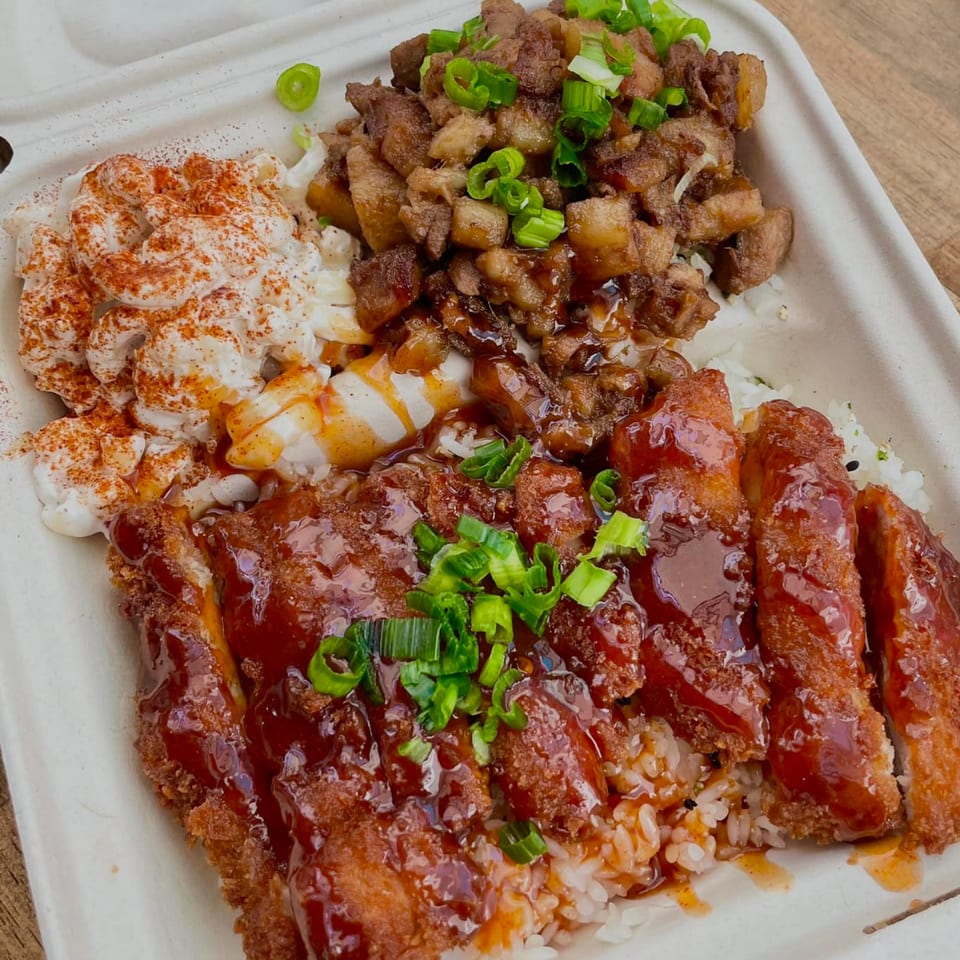 A takeout container with rice, crispy chicken, diced pork, macaroni salad, and green onions.